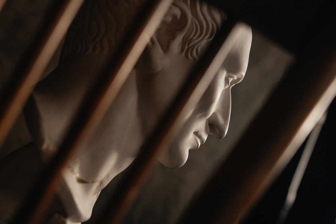 Marble bust of a man behind wooden bars.